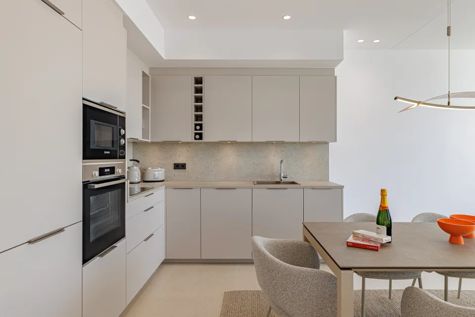 Vacation rental photograph of a modern kitchen with light furniture, integrated appliances and a stylish dining table in Benahavís