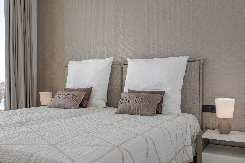 Vacation rental photograph of a bright bedroom with a double bed, cushioned headboards and soft bedside lamps in Benahavís