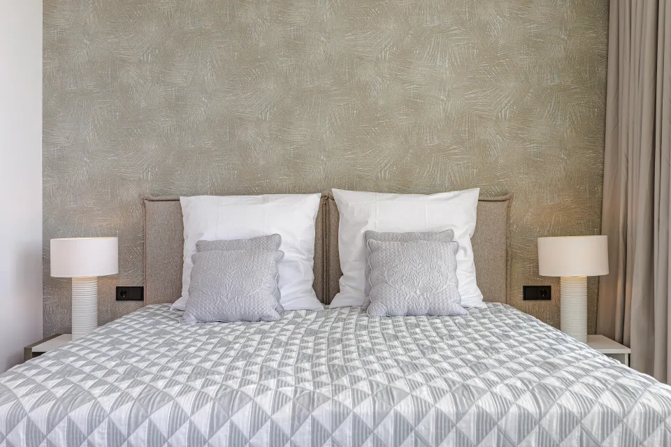 Vacation rental photograph of a cozy bedroom featuring a double bed, soft headboard and white bedside lamps in Benahavís