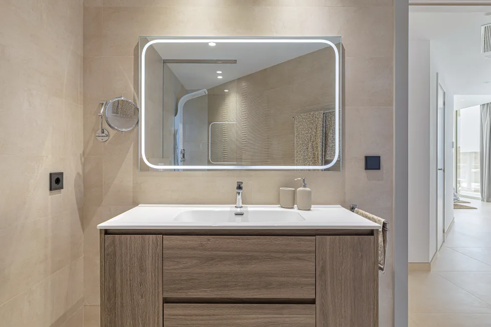 Vacation rental photograph of a sleek bathroom with wooden vanity, illuminated mirror, and walk-in shower in Benahavís
