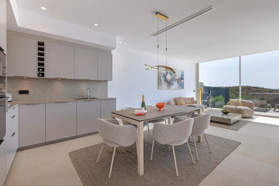 Fotografía de alquiler vacacional de una cocina moderna con mesa de comedor, sillas tapizadas y acceso a terraza en Benahavís