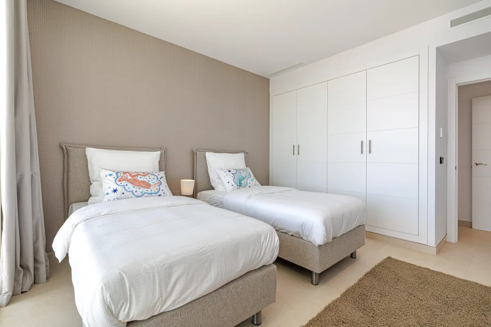 Fotografía de alquiler vacacional de dos camas individuales con ropa de cama blanca y armario empotrado en Benahavís