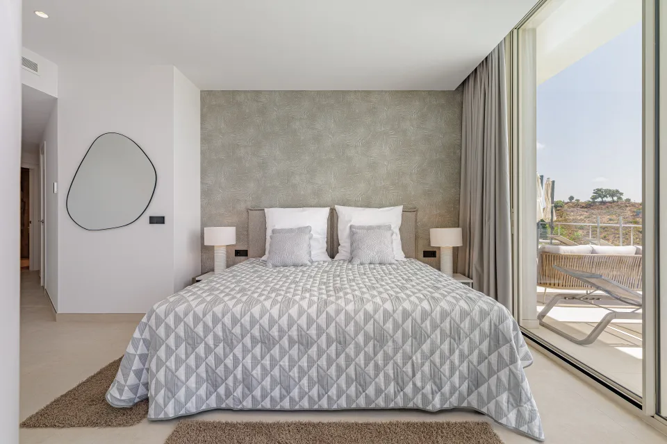 Fotografía de alquiler vacacional de un dormitorio luminoso con cama doble, mesitas de noche y acceso a terraza exterior en Benahavís