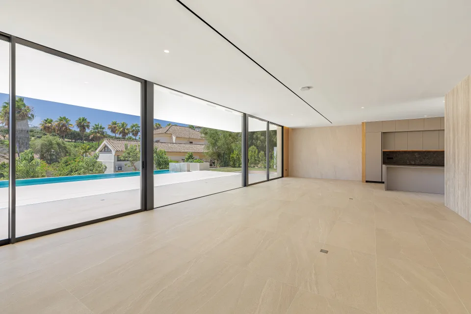 Fotografía de arquitectura de un amplio salón luminoso con grandes ventanales, vistas al jardín en Sotogrande