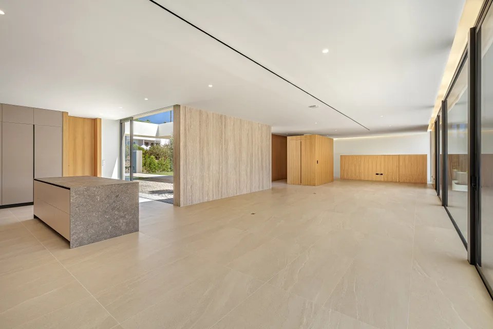 Fotografía de arquitectura de un amplio espacio interior con suelos de piedra, paredes de madera clara en Sotogrande