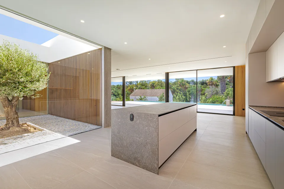 Fotografía de arquitectura de un moderno salón con cocina abierta, isla central de piedra en Sotogrande