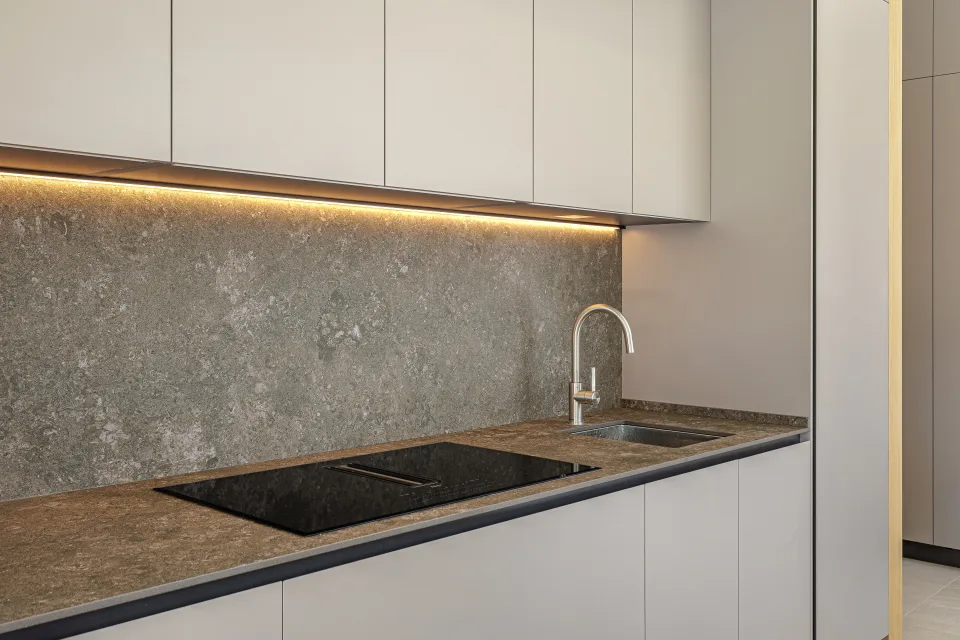 Fotografía de arquitectura de una cocina moderna con encimeras de piedra, grifo minimalista y iluminación suave en Sotogrande