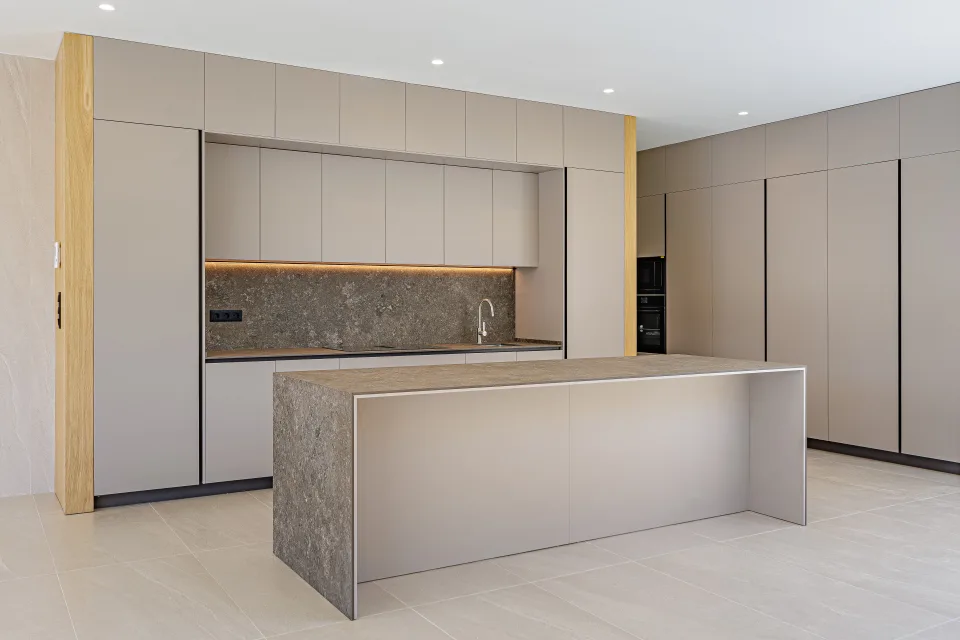 Fotografía de arquitectura de una cocina moderna con encimeras de piedra, grifo minimalista y iluminación suave en Sotogrande