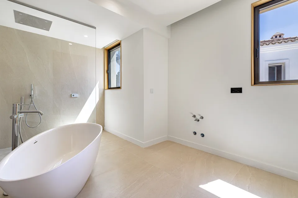 Fotografía de arquitectura de un baño luminoso con bañera exenta, ventanas que ofrecen luz natural en Sotogrande