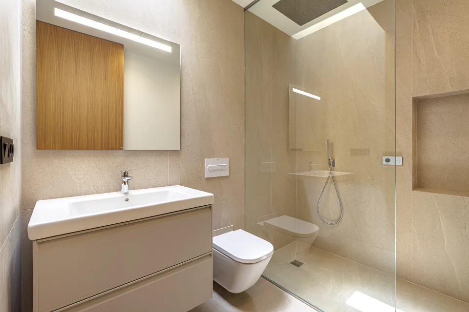 Fotografía de arquitectura de un baño moderno con azulejos beige, lavabo minimalista y ducha a ras de suelo en Sotogrande