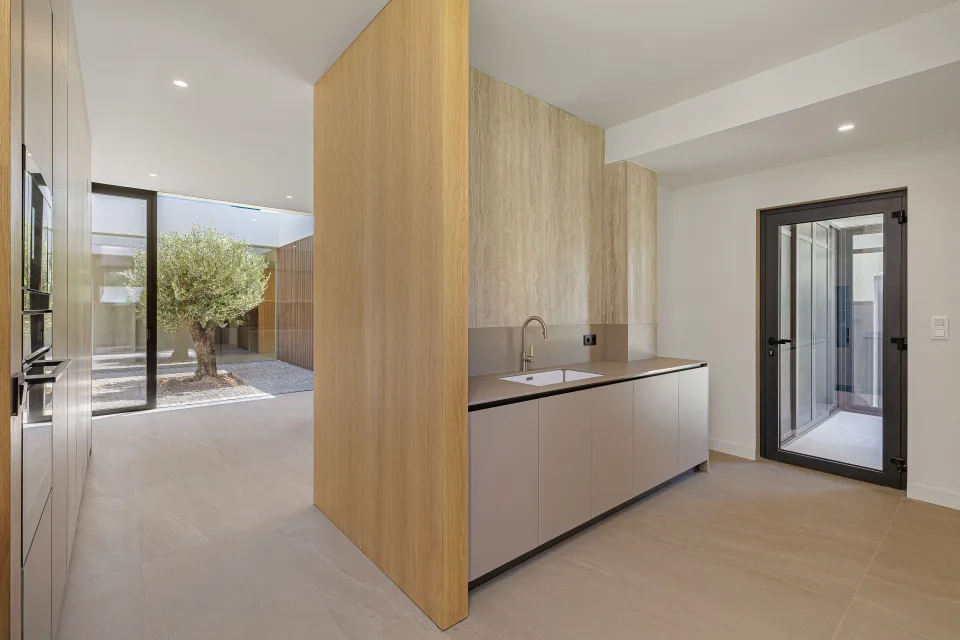Fotografía de arquitectura de una cocina moderna con acabados en madera clara, encimera gris en Sotogrande