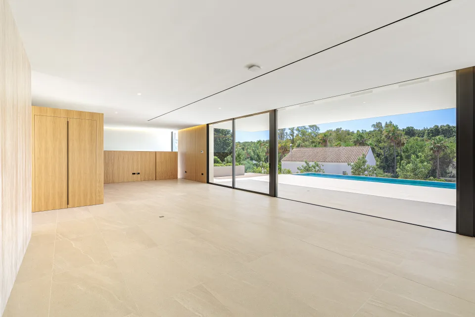 Architectural photograph of a spacious living room with light stone floors, large windows in Sotogrande