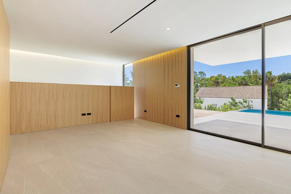 Architectural photograph of a bright living room with light wooden walls and large windows leading in Sotogrande