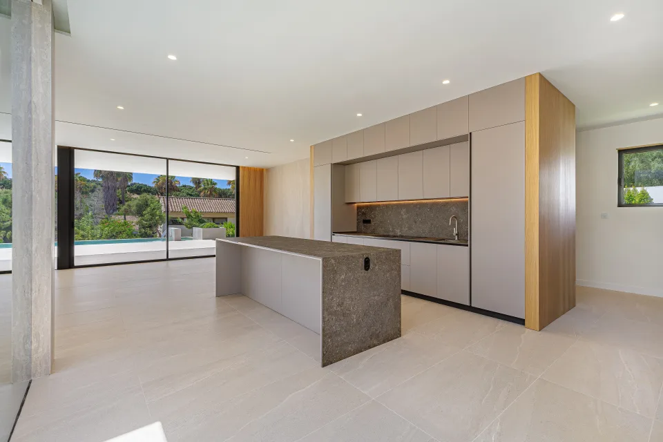 Architectural photograph of a modern living room with open kitchen, central stone island in Sotogrande