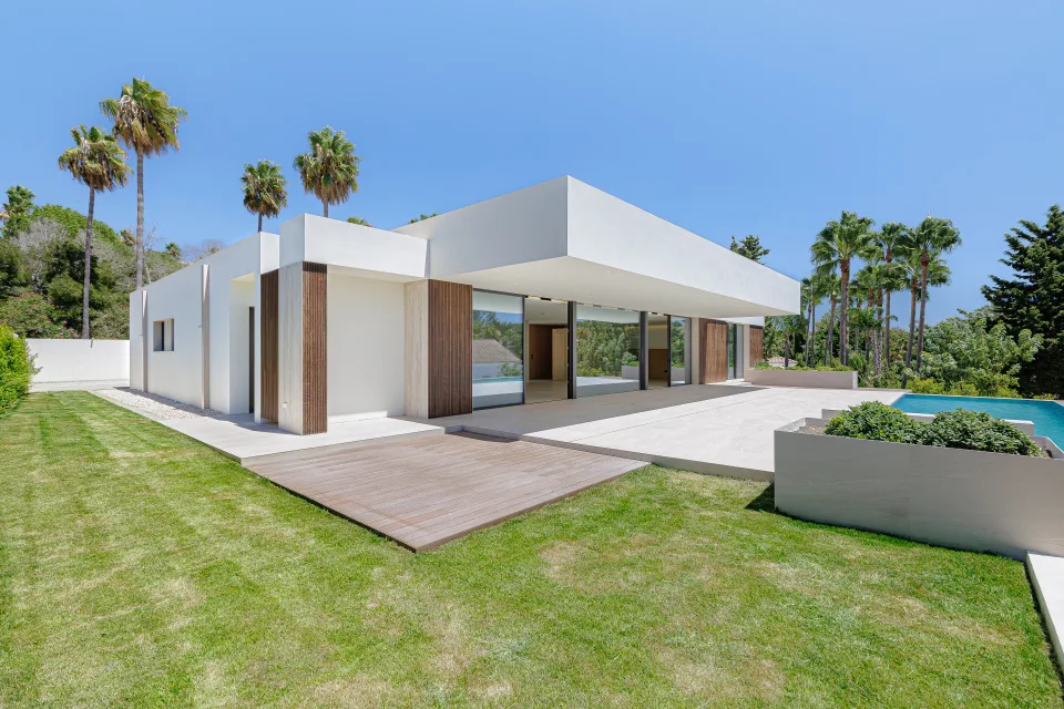 Architectural photograph of a modern villa with large windows, green garden and swimming pool in Sotogrande