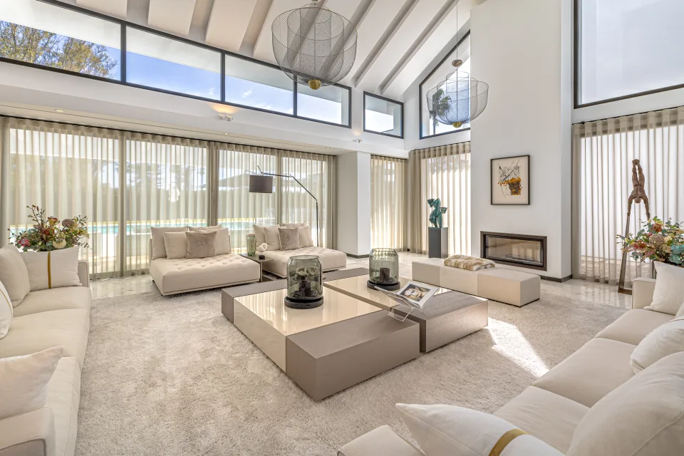 Interior design and architecture photograph of a bright living room with large windows, light sofas and central coffee table in Guadalmina Baja