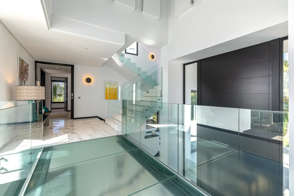 Interior design and architecture photograph of a contemporary hallway with marble stairs, glass railing in Guadalmina Baja