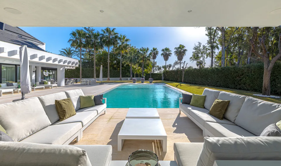 Fotografía de interiorismo y arquitectura de un acogedor salón exterior con sofás claros y cojines en Guadalmina Baja