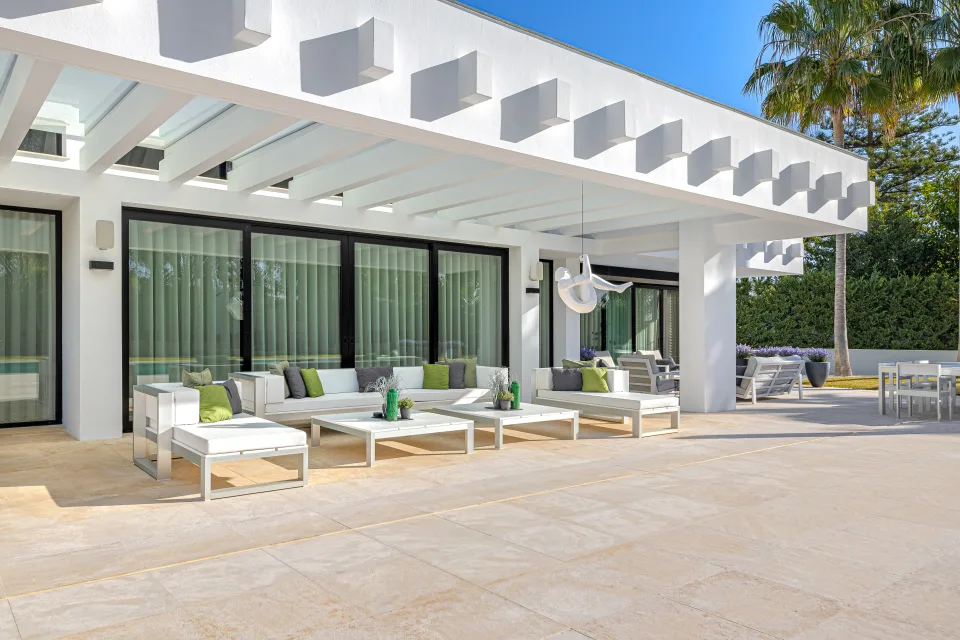 Fotografía de interiorismo y arquitectura de un elegante porche exterior con mobiliario blanco en Guadalmina Baja
