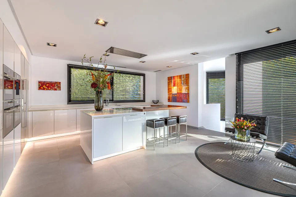 Fotografía de interiorismo y arquitectura de una moderna cocina con muebles blancos, barra de desayuno en Guadalmina Baja