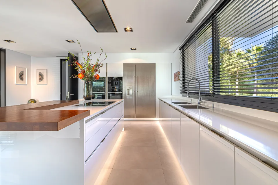 Fotografía de interiorismo y arquitectura de una cocina moderna con superficies brillantes, iluminación suave en Guadalmina Baja