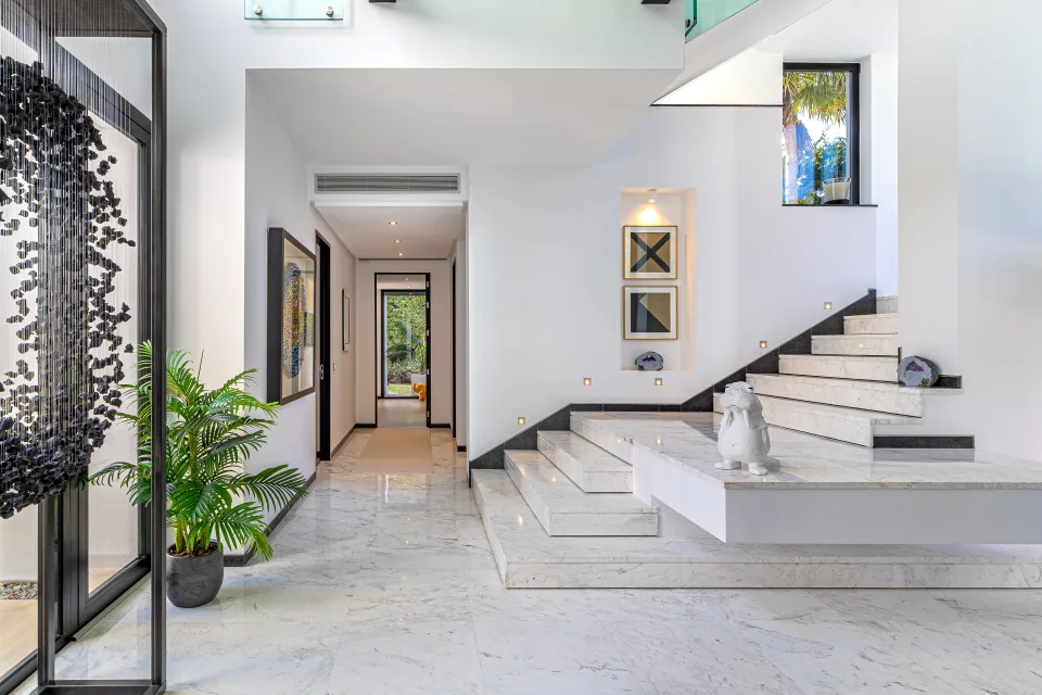 Fotografía de interiorismo y arquitectura de un hall de entrada luminoso con escaleras de mármol y decoración contemporánea en Guadalmina Baja