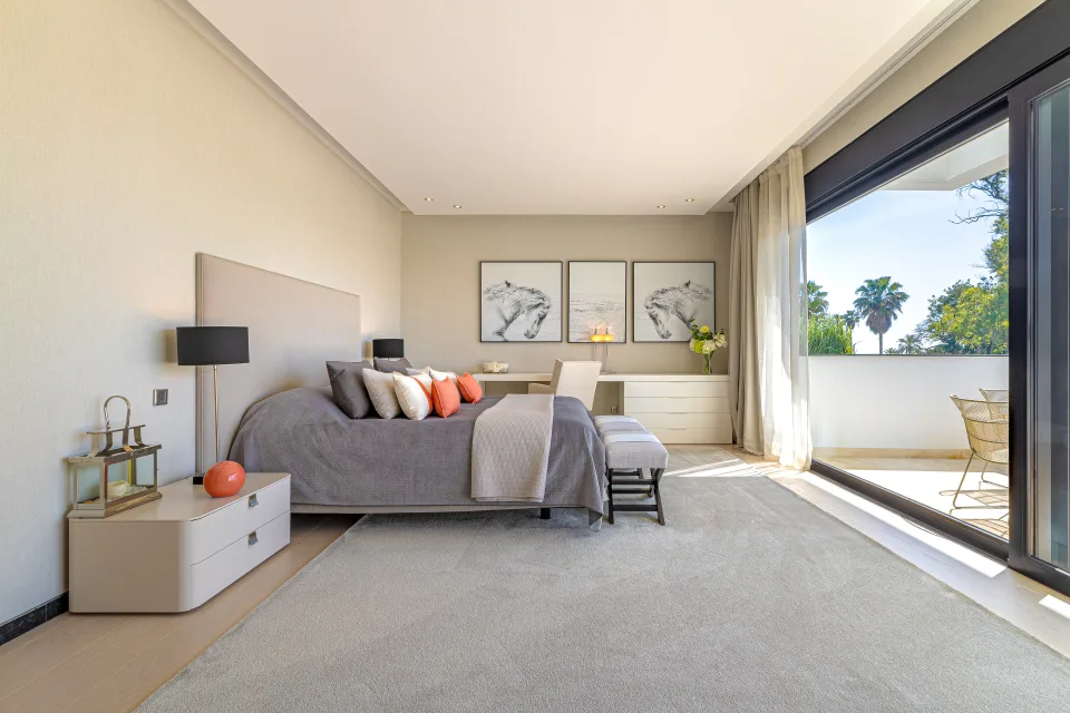 Fotografía de interiorismo y arquitectura de un dormitorio moderno con luz natural, cama amplia y acceso a balcón en Guadalmina Baja