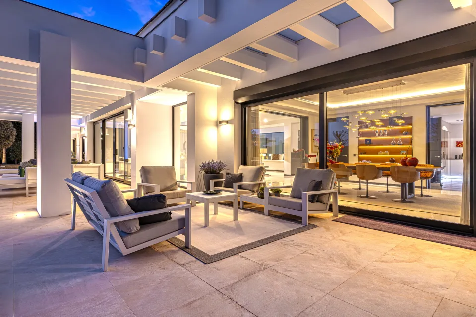 Fotografía de interiorismo y arquitectura de un acogedor porche con mobiliario de exterior, iluminación cálida en Guadalmina Baja