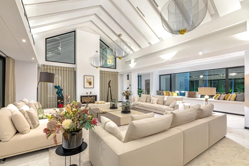 Fotografía de interiorismo y arquitectura de un amplio salón con techos altos, grandes ventanales y decoración elegante en Guadalmina Baja