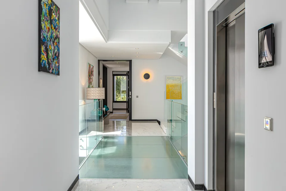 Fotografía de interiorismo y arquitectura de un amplio vestíbulo con suelo de mármol, paredes blancas en Guadalmina Baja