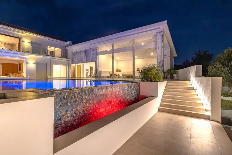Real estate photograph of a modern villa with illuminated pool and elegant stairs in Marbella