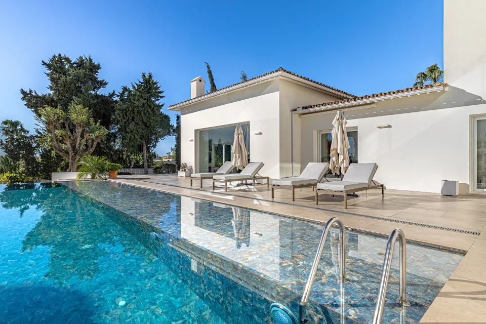 Real estate photograph of a stylish villa with infinity pool and comfortable sun loungers in Marbella