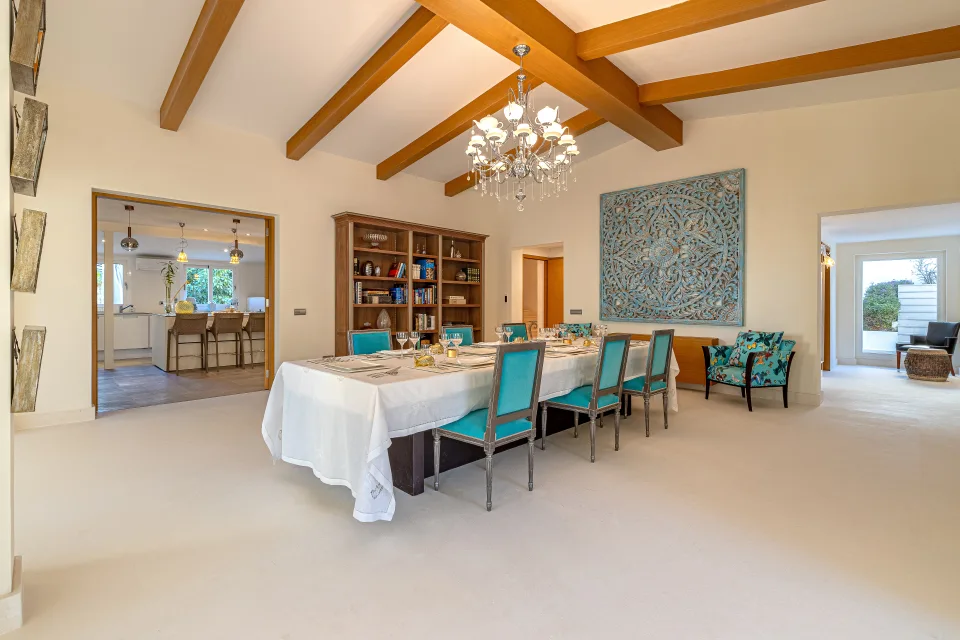 Real estate photograph of a spacious dining room with a rectangular table, blue chairs and decorative wall details in Marbella