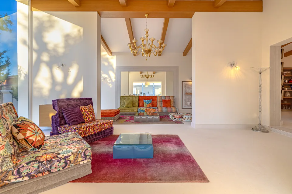 Real estate photograph of a bright living room with colorful sofas, glass table and decorative details in Marbella