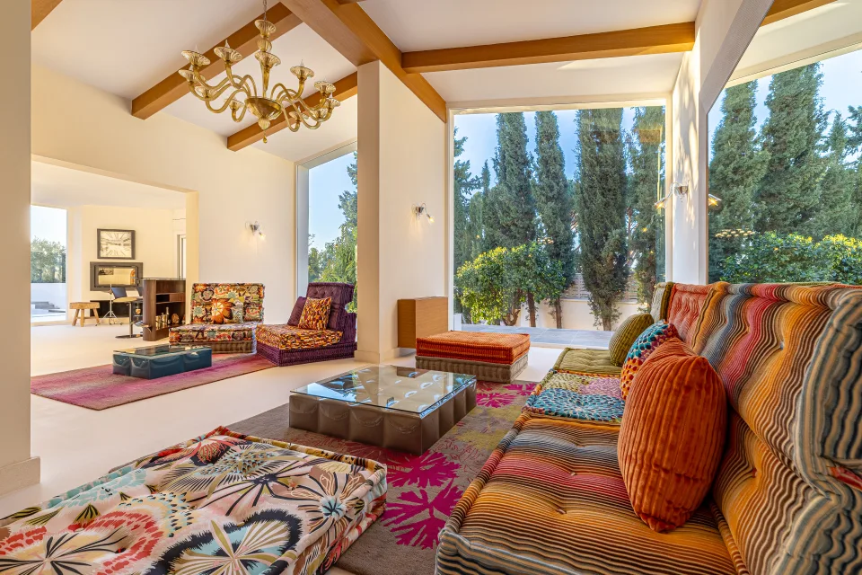 Real estate photograph of a bright living room with large windows, colorful sofas and an elegant coffee table in Marbella