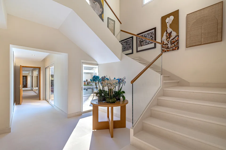 Real estate photograph of an elegant hall with a modern staircase, wooden details and minimalist decor in Marbella