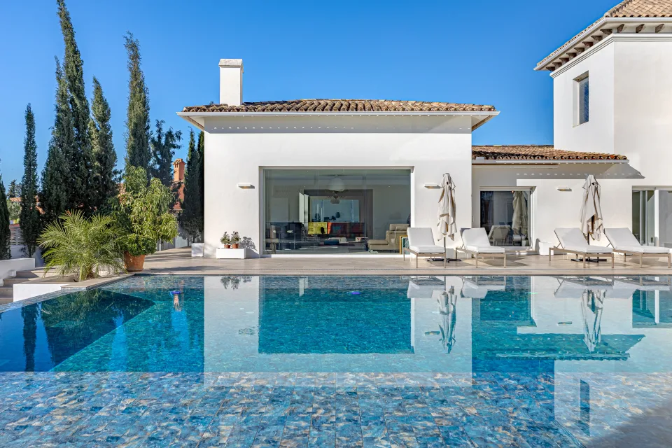Fotografía inmobiliaria de una villa moderna con piscina, jardín y amplias ventanas que aportan luz natural en Marbella