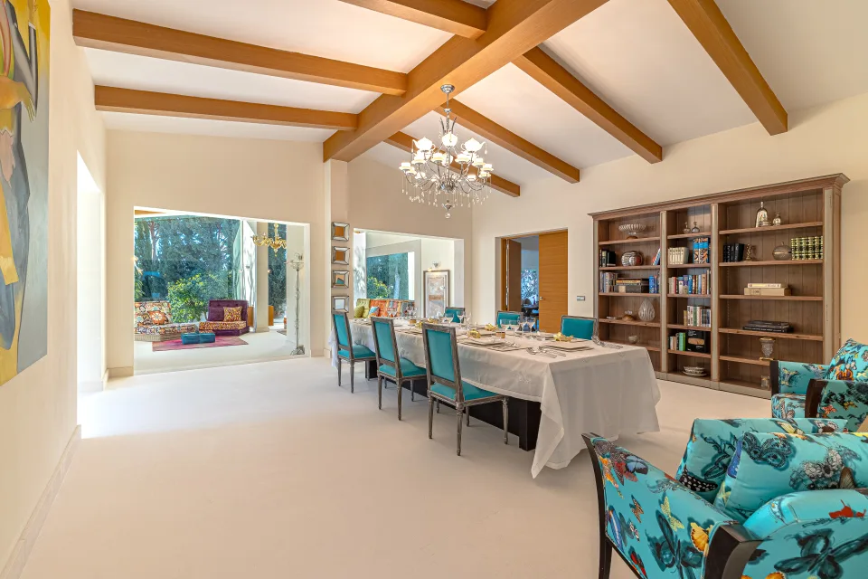 Fotografía inmobiliaria de un espacioso comedor con mesa para diez, sillas coloridas y acceso a jardín en Marbella
