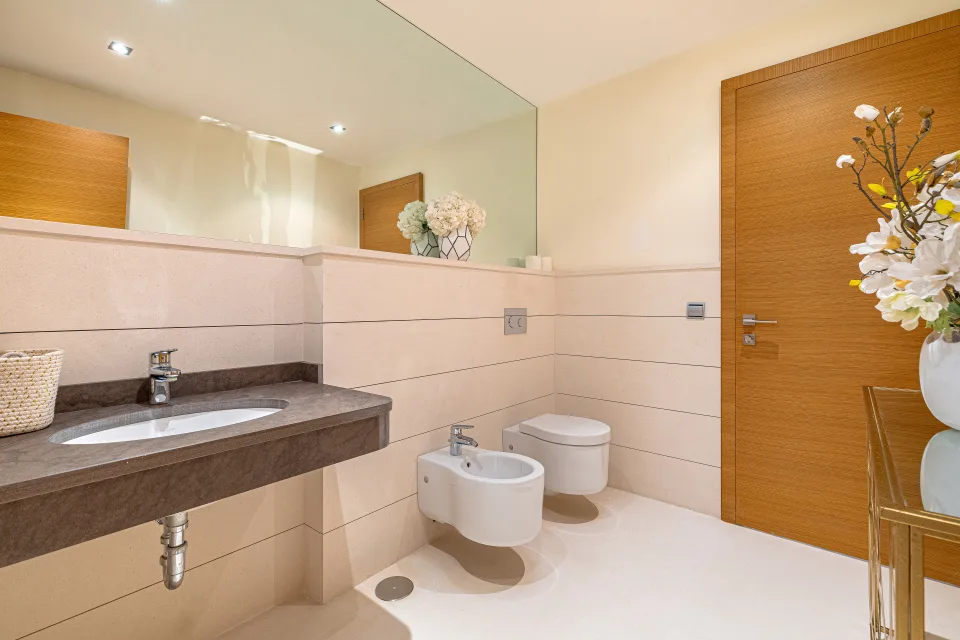 Fotografía inmobiliaria de un moderno baño con lavabo de mármol, bidet y decoración minimalista en Marbella