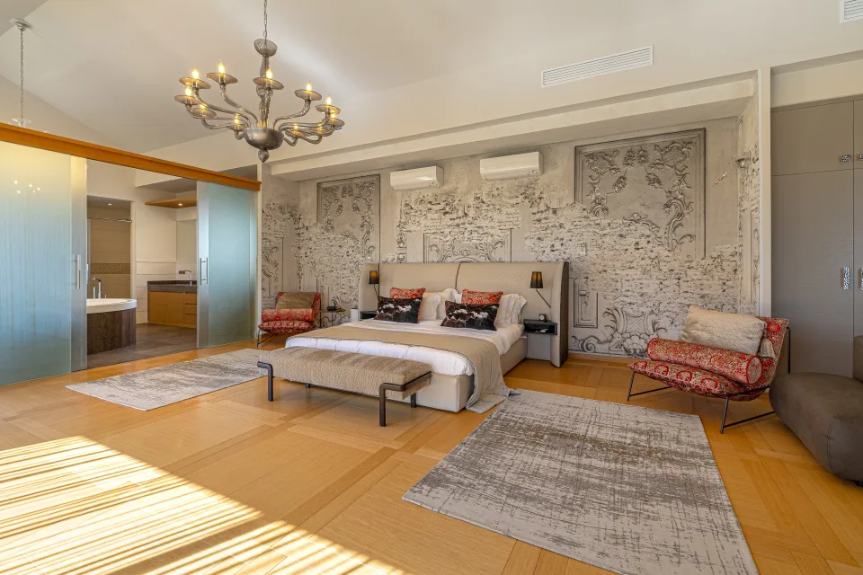 Fotografía inmobiliaria de un amplio dormitorio con cama king size, lámpara moderna y decoración elegante en paredes en Marbella