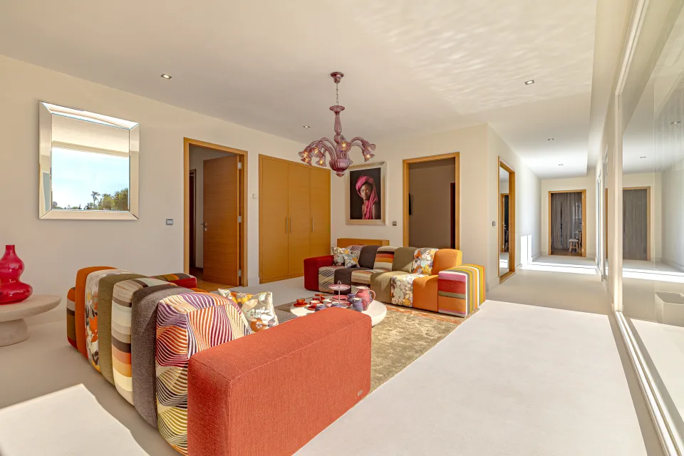 Fotografía inmobiliaria de un acogedor salón con muebles coloridos, iluminación clara y gran ventanal en Marbella