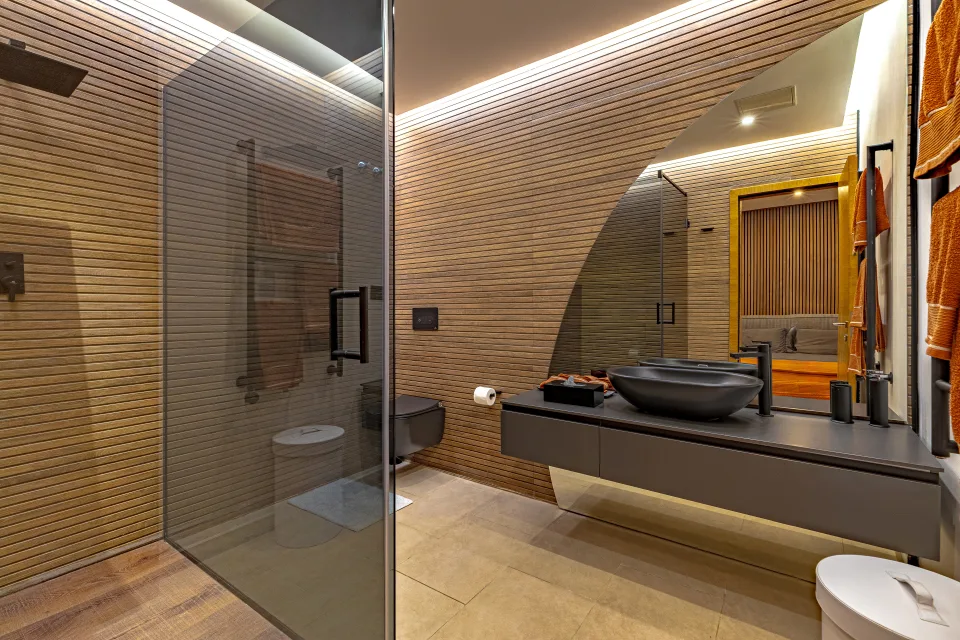 Fotografía inmobiliaria de un elegante baño con paredes de madera, lavabo moderno y ducha espaciosa en Marbella