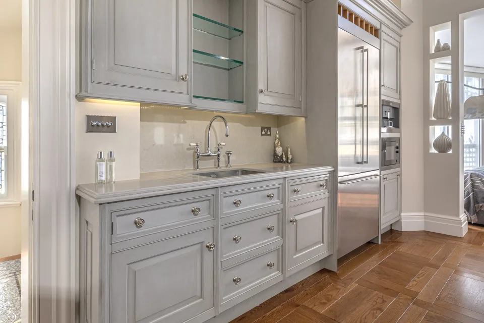 Fotografía inmobiliaria de una cocina moderna con muebles en tonos claros, encimera de piedra y electrodomésticos de acero inoxidable en Londres