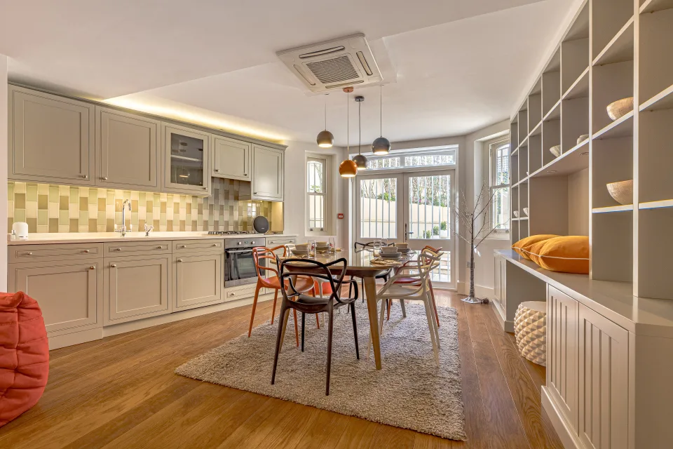 Fotografía inmobiliaria de una cocina moderna con mobiliario claro, mesa de comedor y zonas de almacenamiento en Londres
