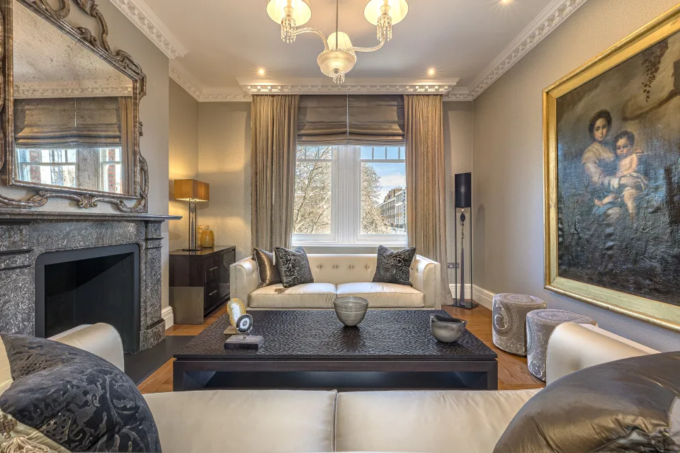 Fotografía inmobiliaria de un salón elegante con sofás claros, mesas decorativas y una chimenea moderna en Londres