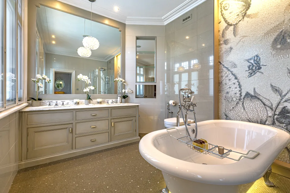 Fotografía inmobiliaria de un elegante baño con bañera exenta, mobiliario en tonos suaves y detalles decorativos en mosaico en Londres