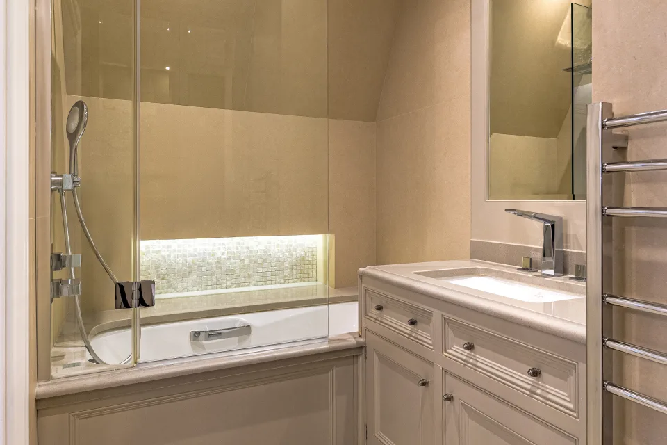 Fotografía inmobiliaria de un cuarto de baño elegante con ducha y bañera iluminada, lavabo moderno y azulejos claros en Londres