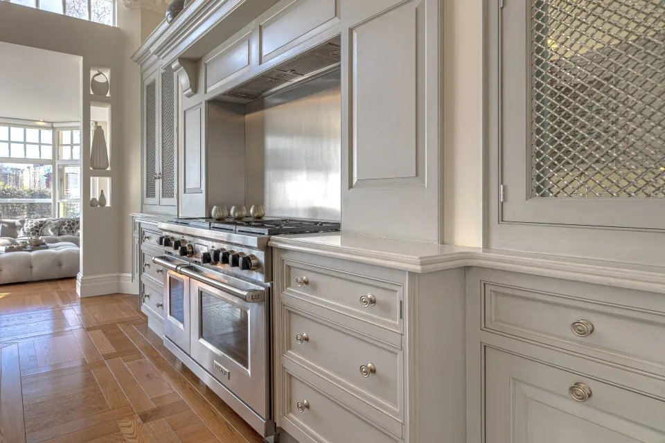 Real estate photograph of a modern kitchen with light finishes, stainless steel appliances and elegant storage space in London