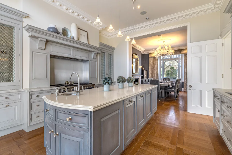 Real estate photograph of a stylish kitchen with grey cabinetry, marble countertops and classic design details in London