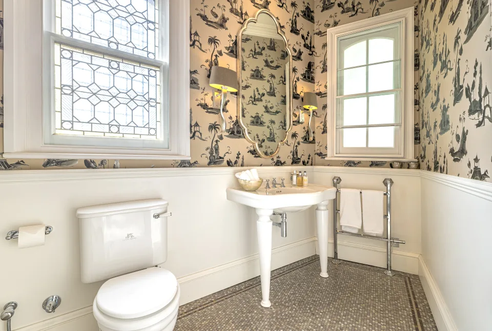 Real estate photograph of a cozy bathroom featuring decorative tiles, pedestal sink and natural light in London